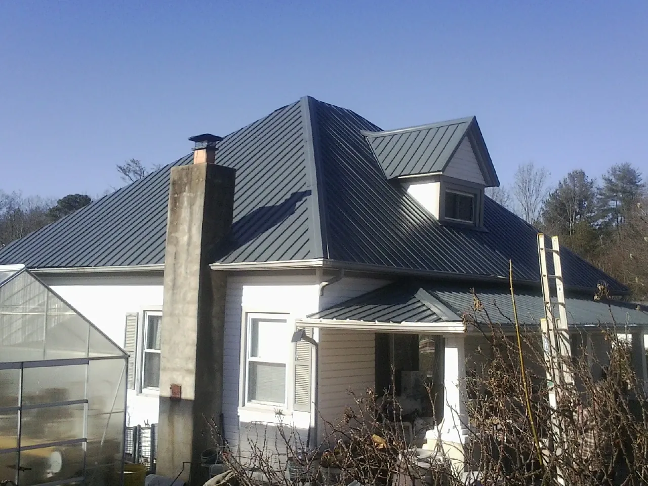 Dark blue standing seam metal roof on a white farmhouse with dormer — Slate & Tile Roof Repair by Roofing Brothers in Husum