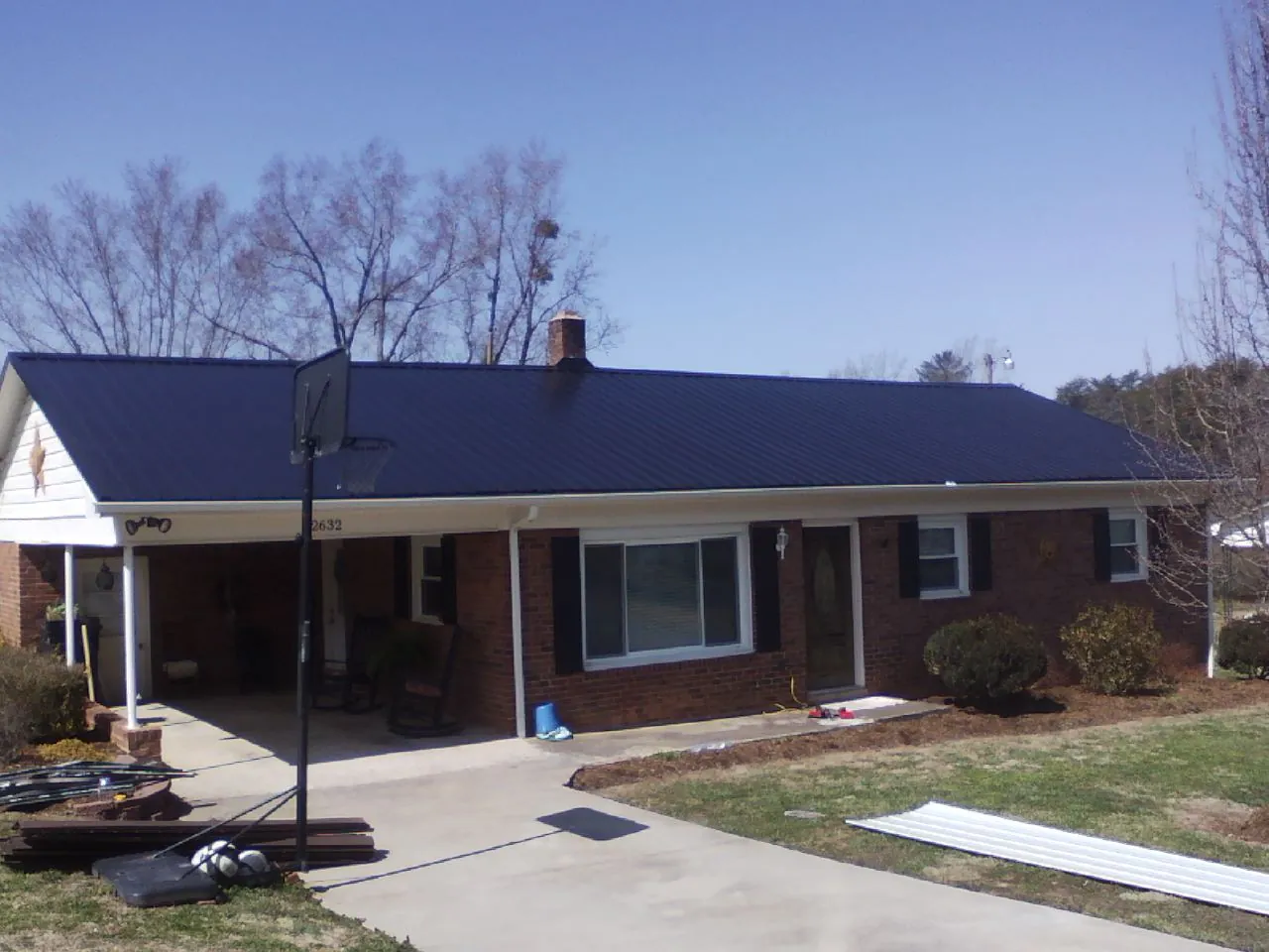 Finished dark blue metal roof on a brick ranch with a carport in Husum