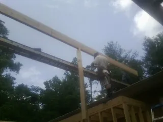 Carpenter setting a ridge beam over a new addition frame — Ice Dam Removal by Roofing Brothers in Husum