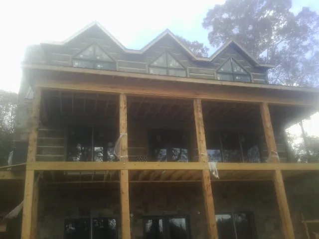 Dormers and porch framing on a large log home under construction — Roof Coating work by our crew in Husum