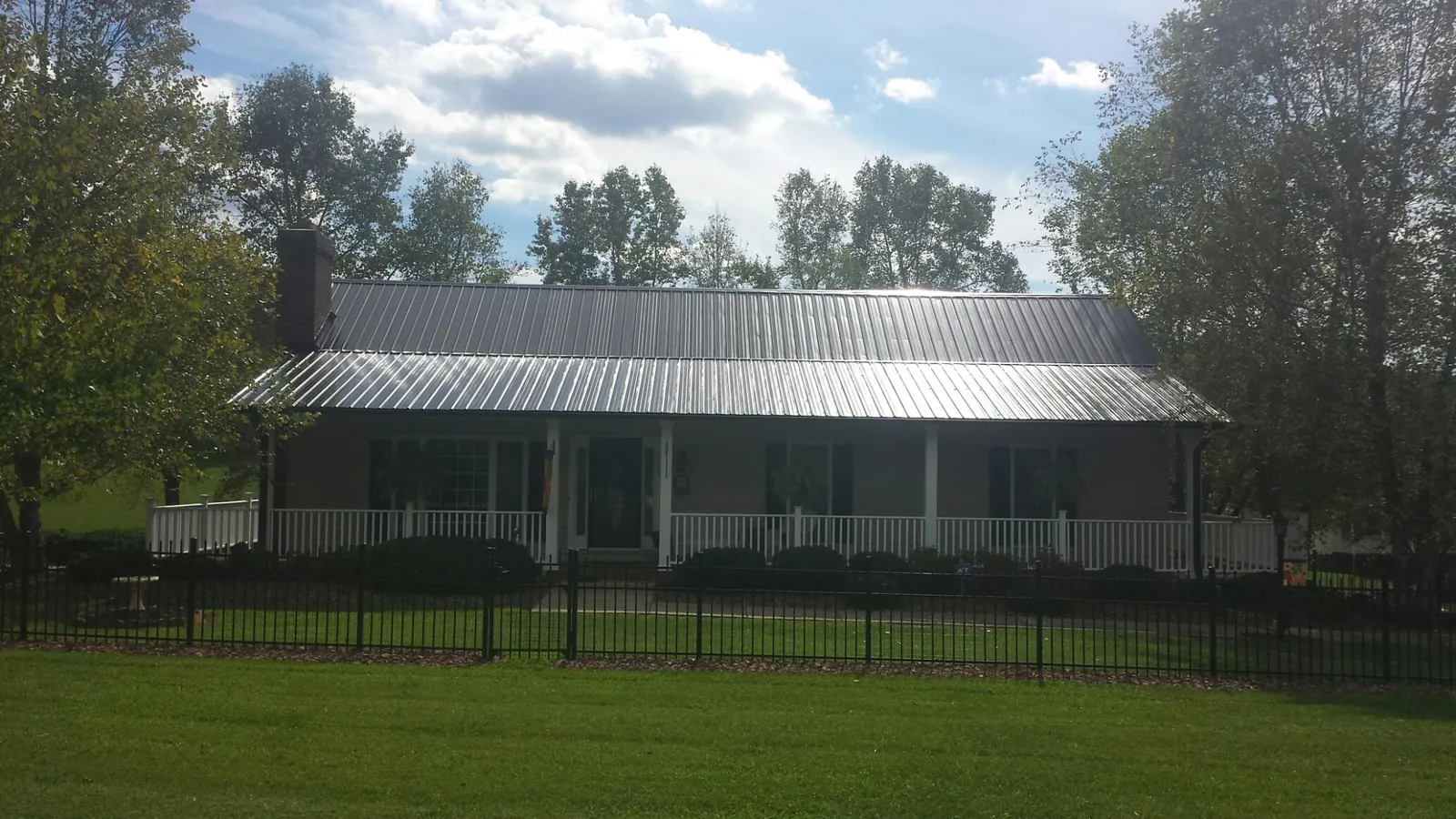 Gray metal roof on a brick ranch with a full width front porch — Gutter Guard Installation work by our crew in Husum