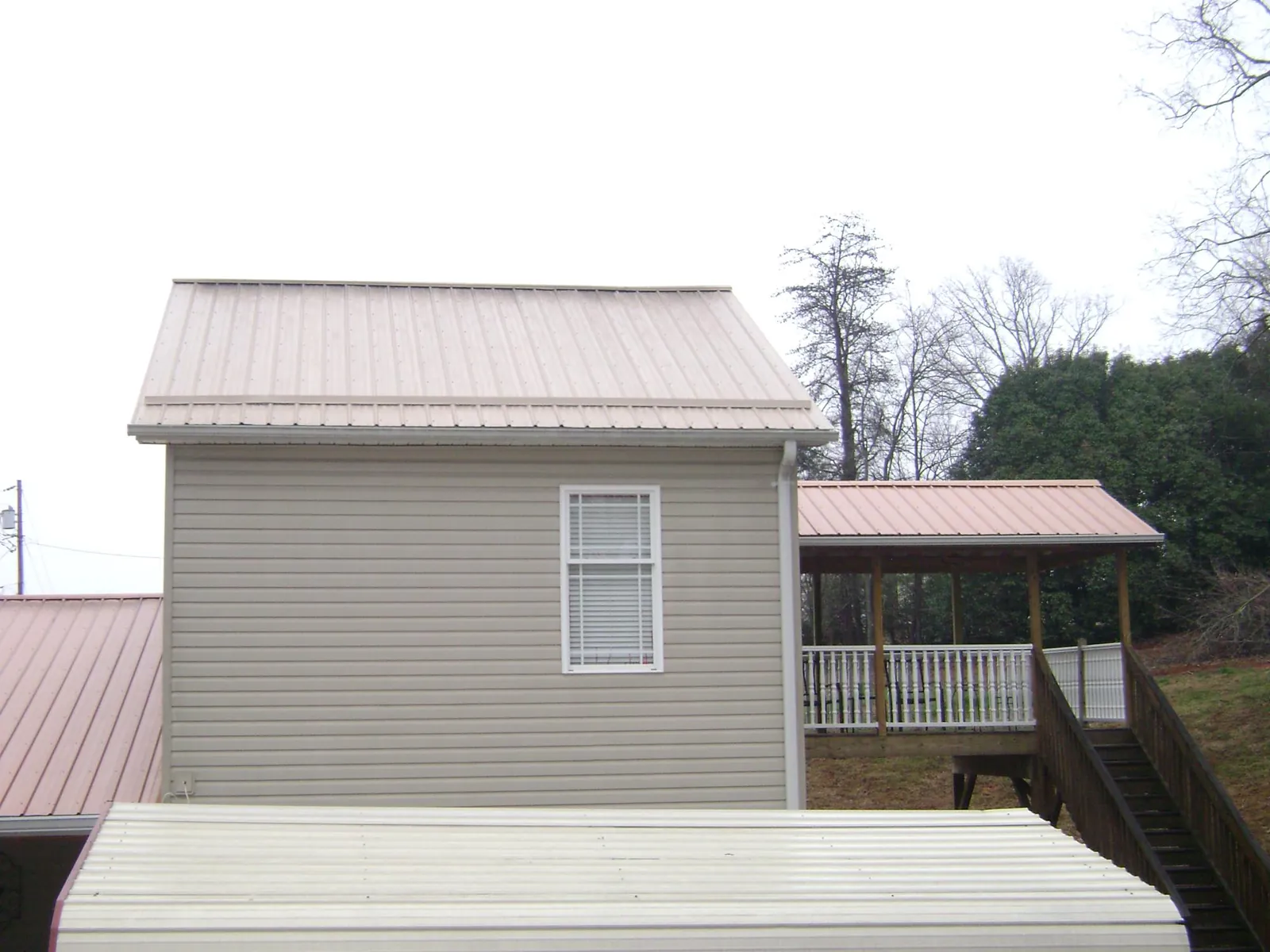 Tan metal roofs on a two story addition and attached porch, from a Roof Replacement job in Husum