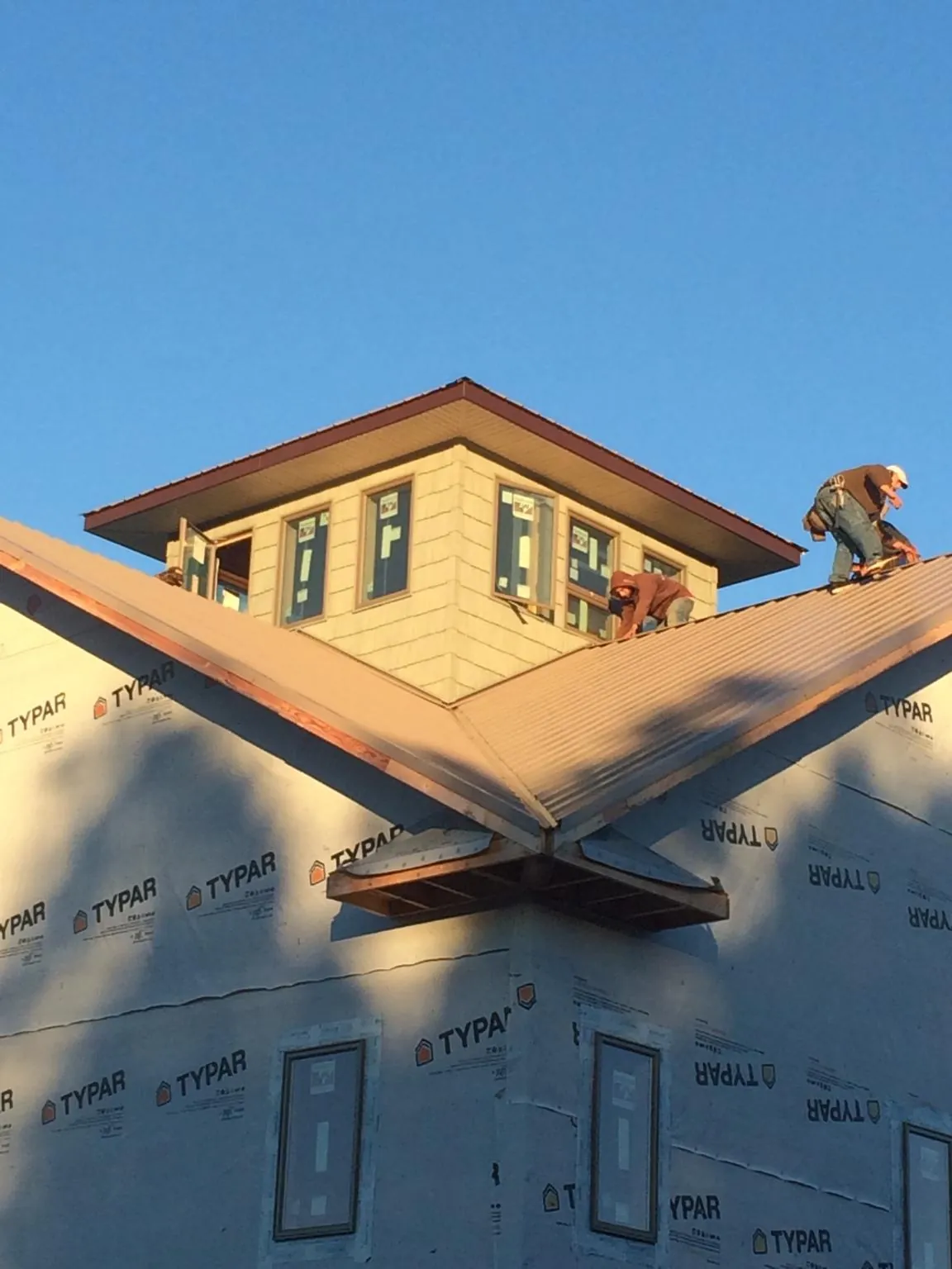 Roofers working around a rooftop cupola on a new metal roof at sunset — Roof Waterproofing in Husum by Roofing Brothers